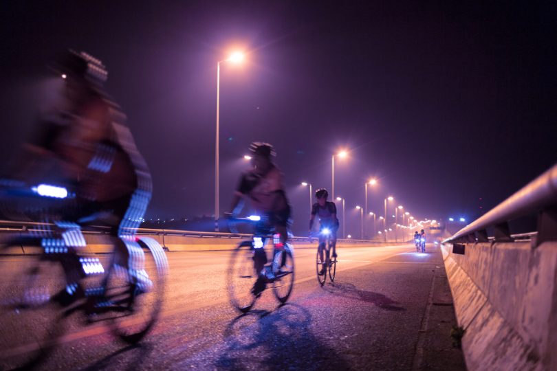 Blurry of Cyclists ride through lighted city.Background.