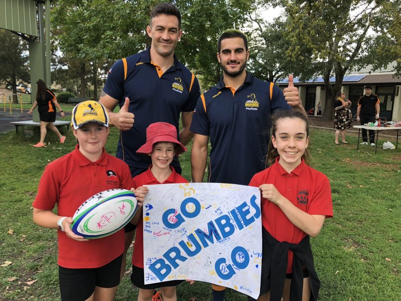 Two Brumbies players with three young school students