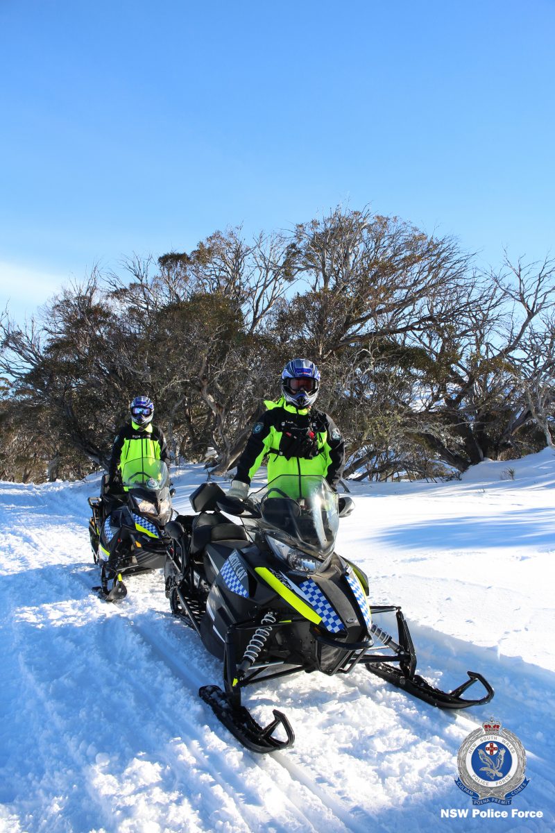 Two NSW Police officers on snow mobiles on ski field.