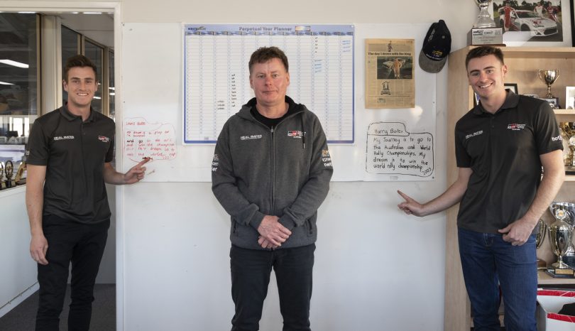 Lewis Bates, Neal Bates and Harry Bates in front of whiteboard with their childhood dreams written on it. 