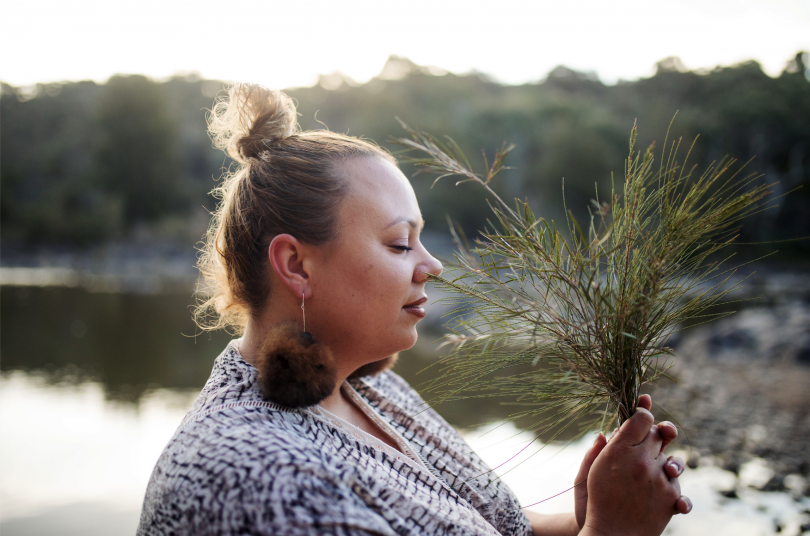 Krystal Hurst outdoors holding native plant.