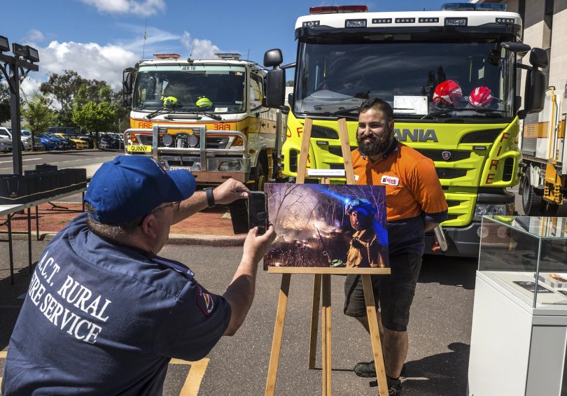 Volunteer firefighter posing with artwork in front of firetruck.