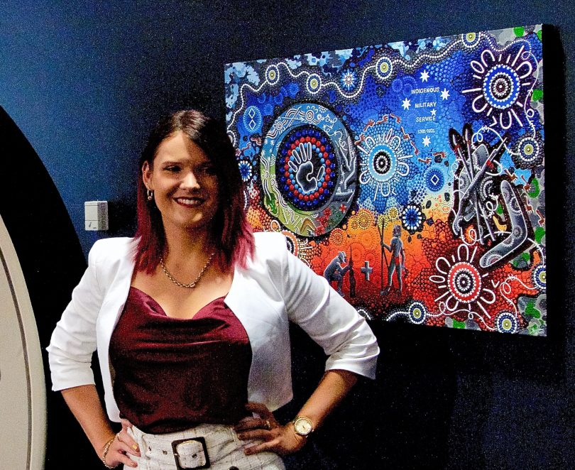 Indigenous artist Chern'ee Sutton in front of her artwork that inspired the coin