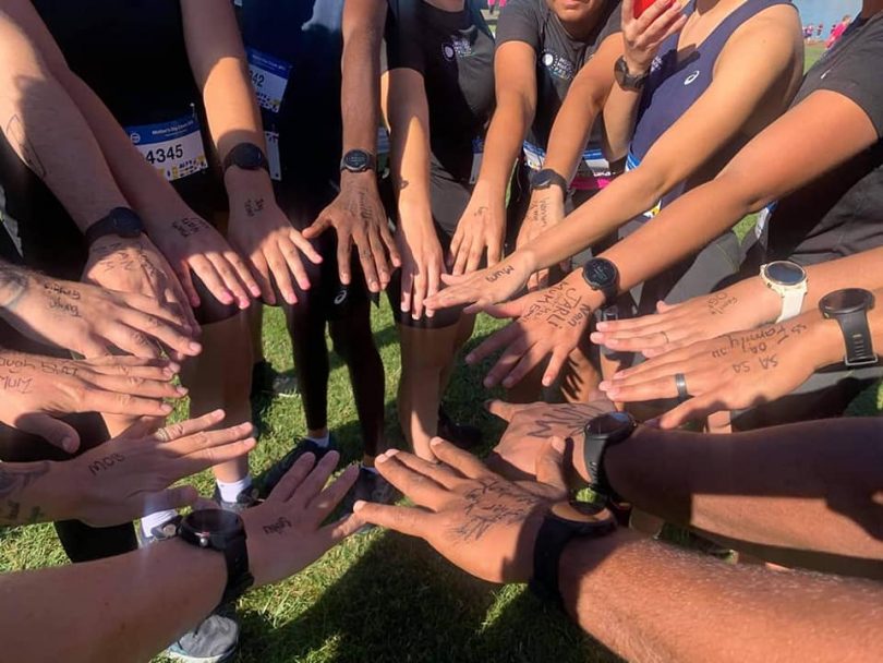 Indigenous Marathon Foundation members placing hands in circle