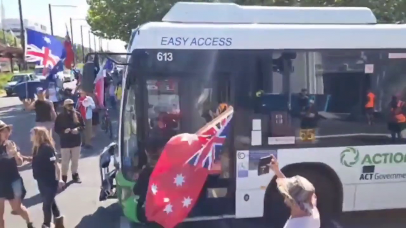 Protesters with AuUstralian flags next to a bus