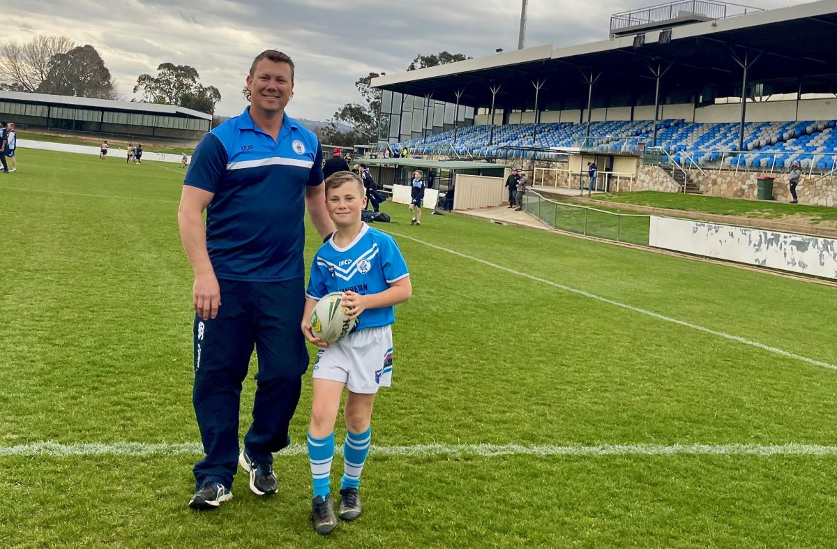 Father and son rugby league players standing on football field together