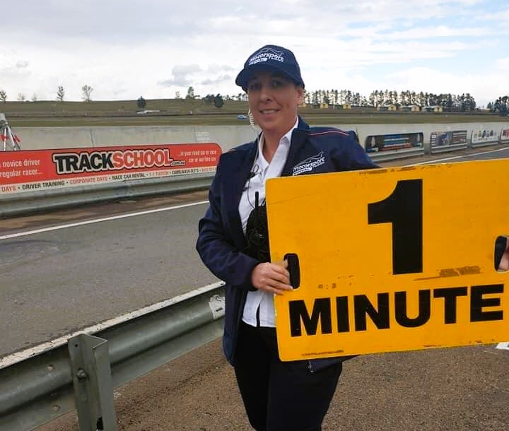 Woman holding sign at a racetrack 
