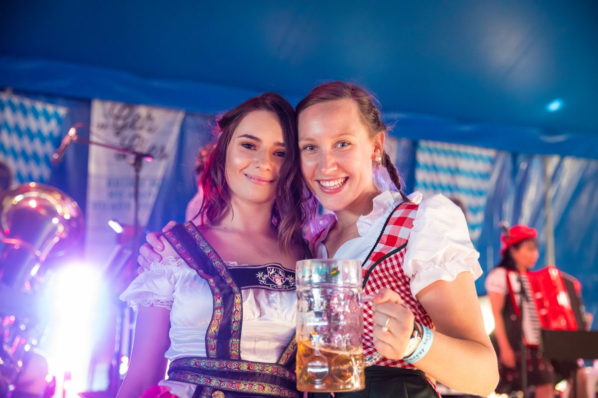 Two women in traditional German costume, one holding a mug of beer