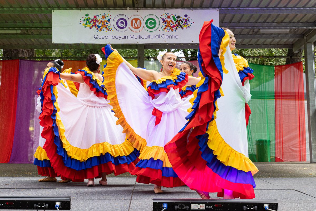 Several female dancers in colourful dresses dancing on stage at the 2022 Queanbeyan Multicultural Festival.