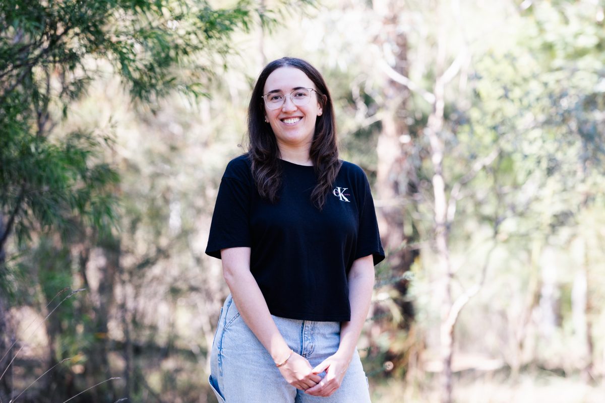 PhD candidate Emily Stringer standing in a bushland setting.