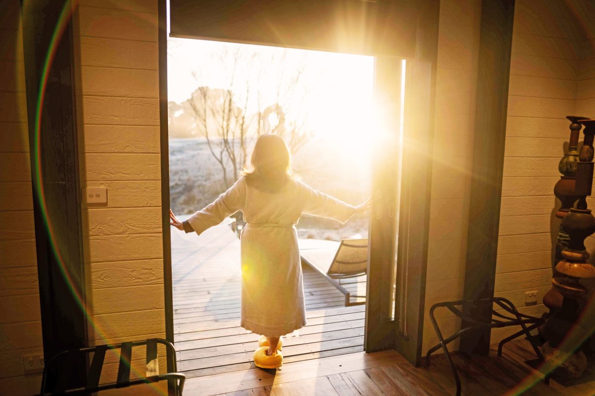 a woman standing in a door looking at the sunrise