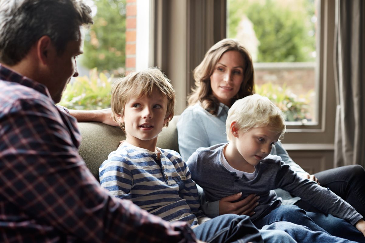 Shot of a family of four sitting together on their living room sofa