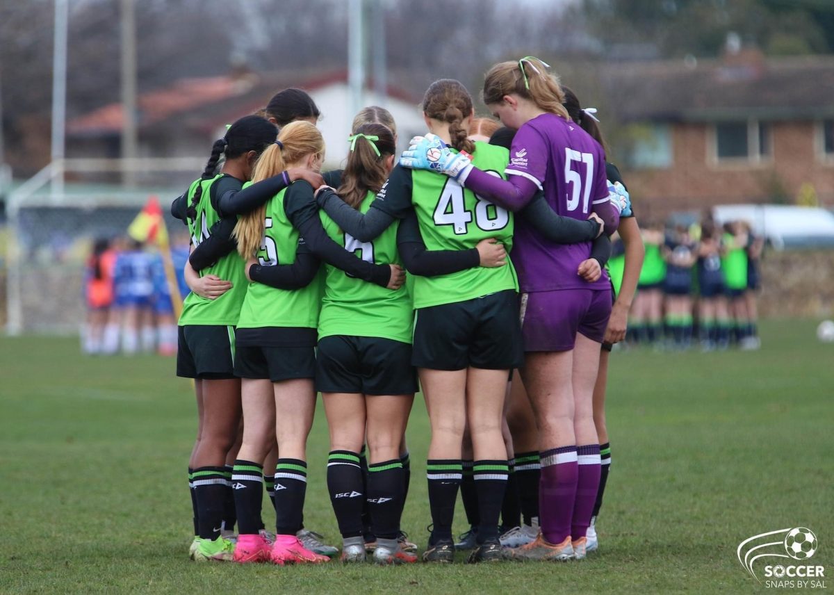 CUA girl's football team in a group huddle