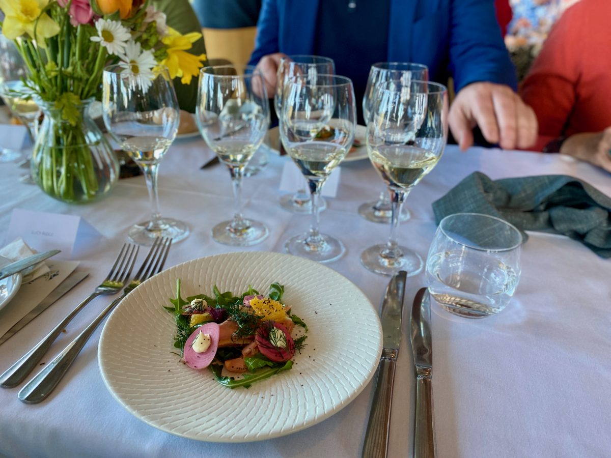 Plate of smoked salmon and salad on table with wine glasses