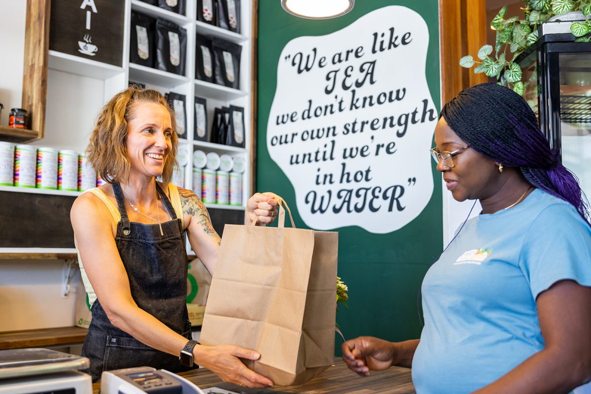 shopkeeper handing a paper bag to a customer