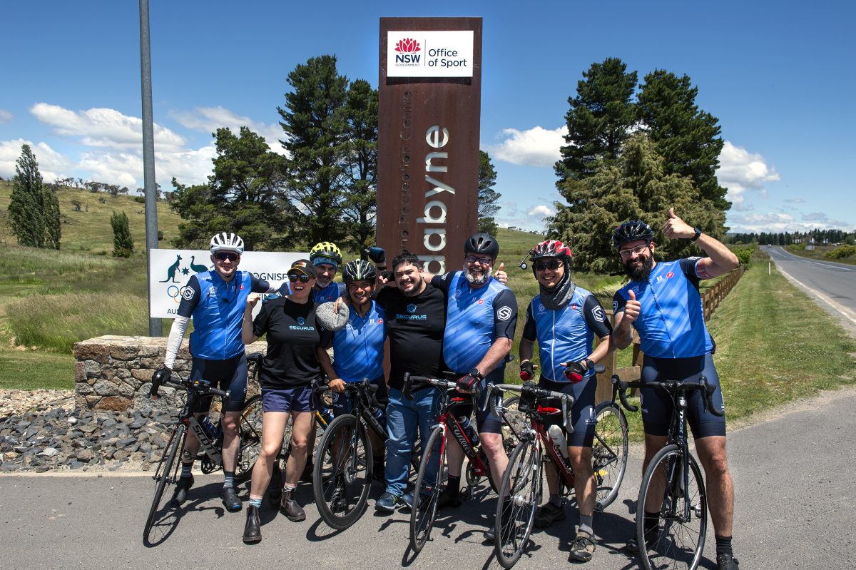 Cyclists pose in front of a sign at Jindabyne.