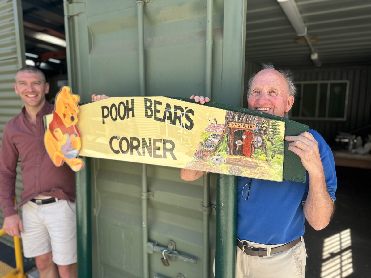 Pooh Bear's Corner sign being held by two men