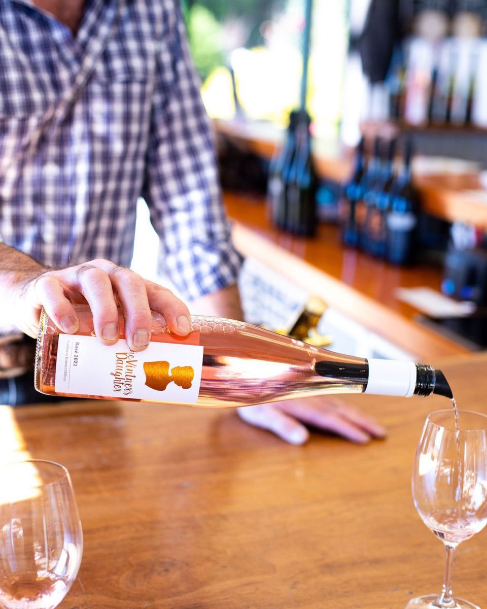 A hand pouring wine into a glass