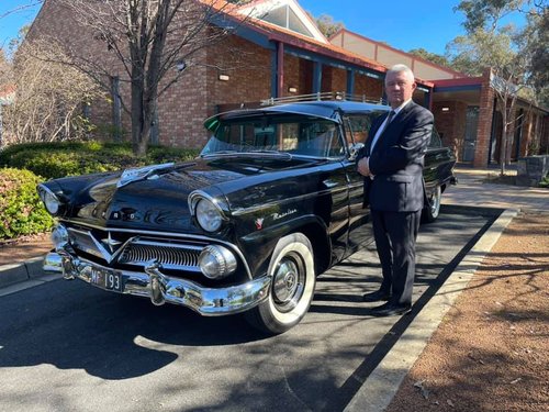 Bill cole alongside a black Ford hearse