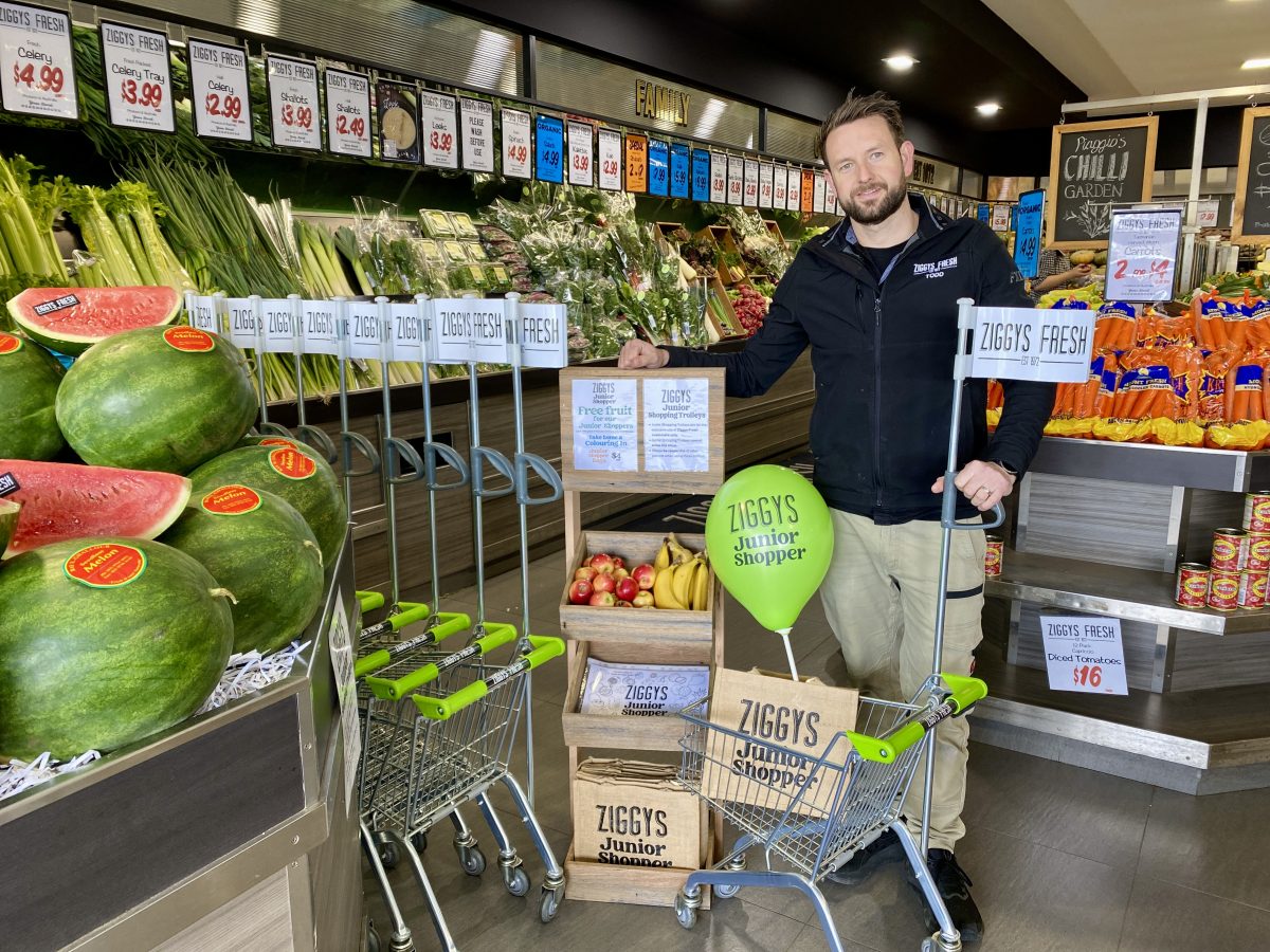 Todd stands with a child-sized trolley branded Ziggy's Fresh.