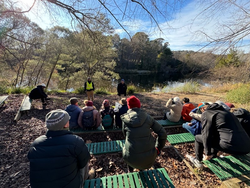 People seated listening to a man standing in front of them