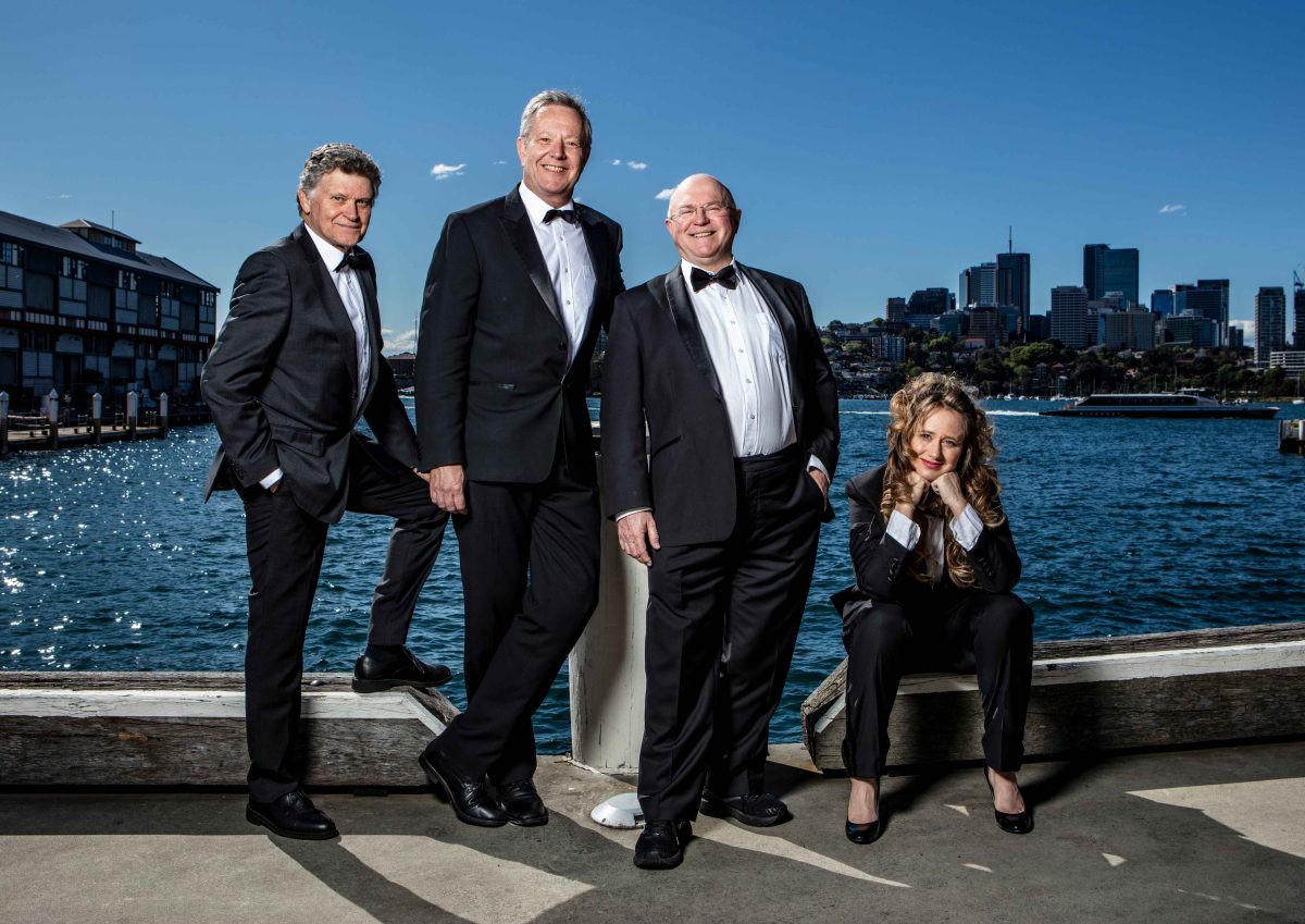 four people standing and sitting on a wharf