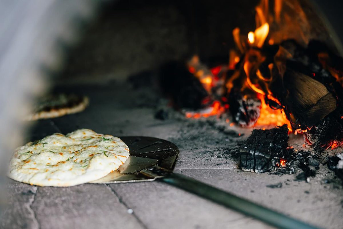 A pizza cooking in a wood fired oven.