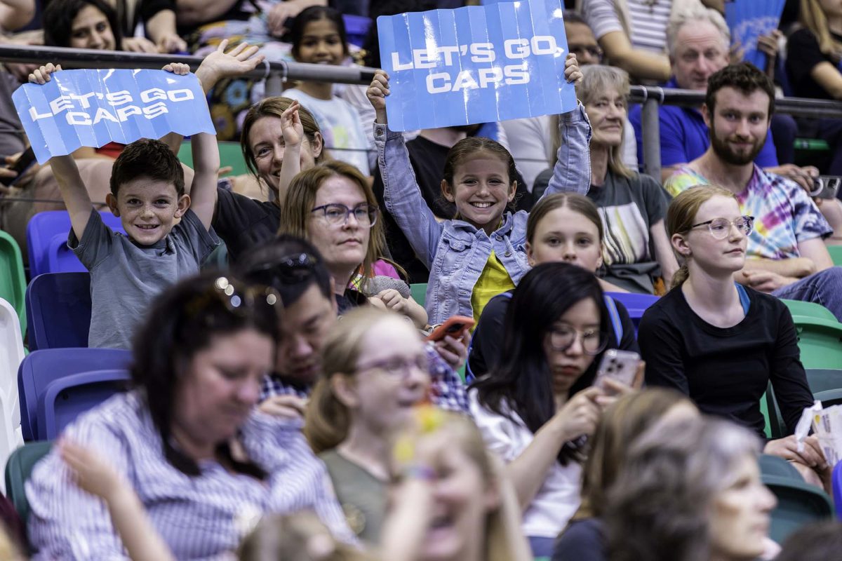 children holding signs in a crowd at a basketball game. 