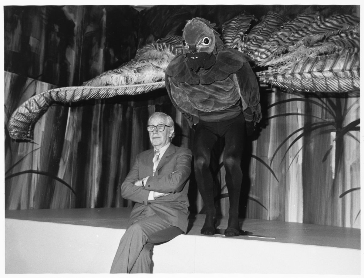 Black and white photo of man seated on the edge of the stage