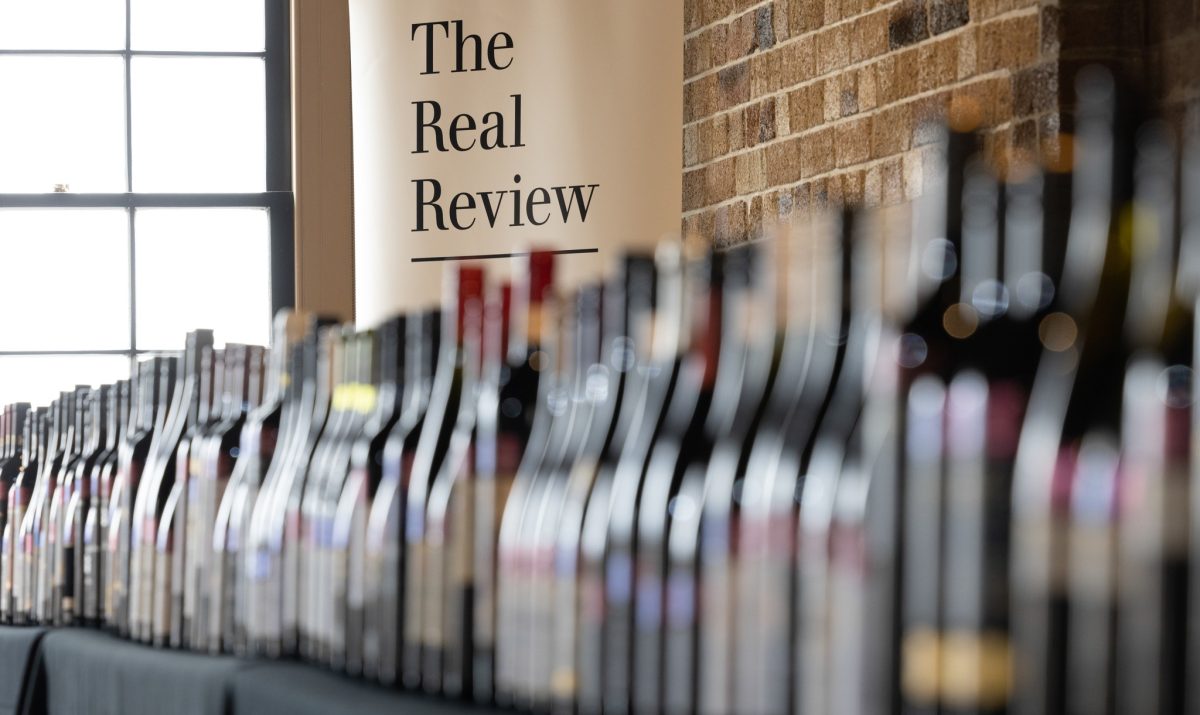 Banner reading 'The Real Review' behind a lineup of many wine bottles.