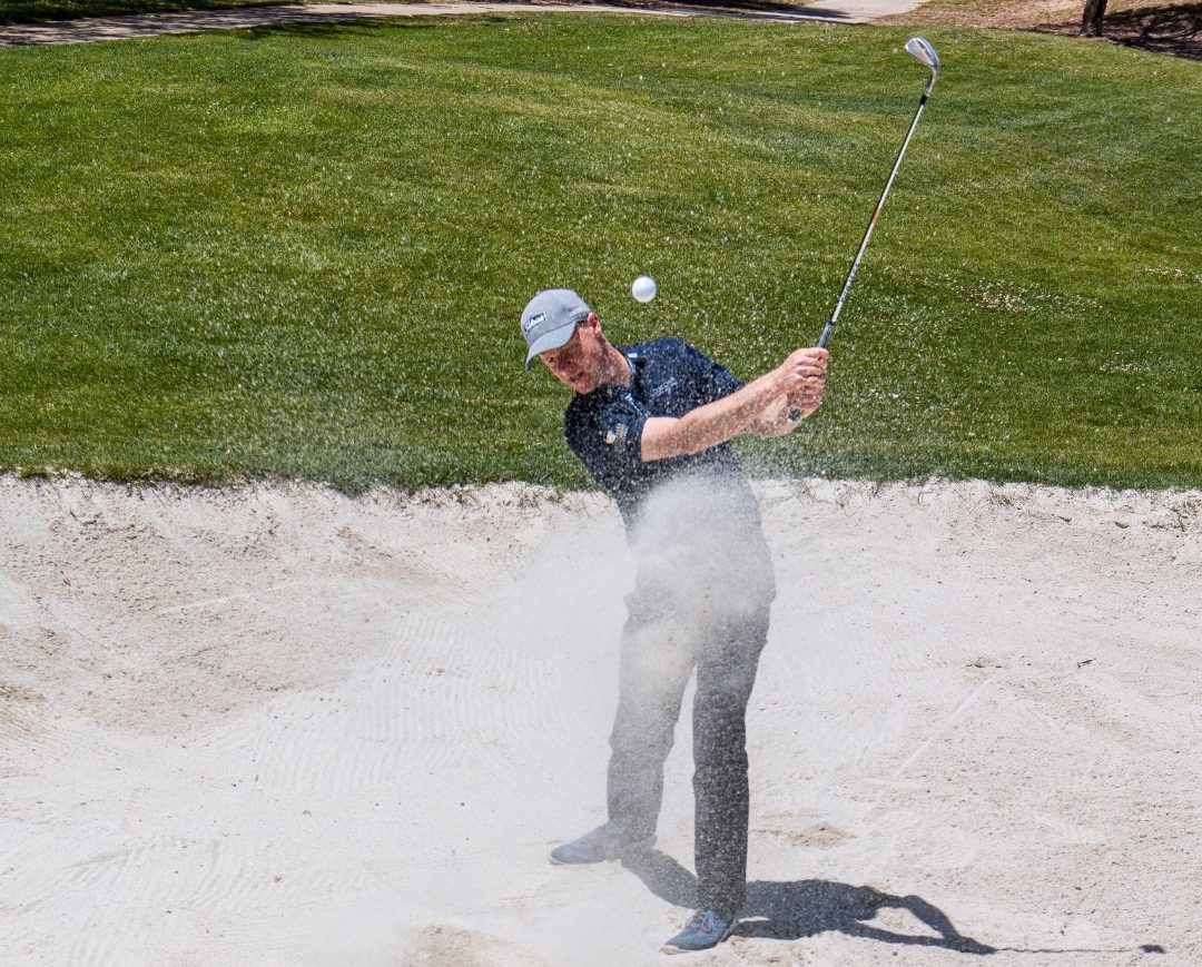 Golf coach Damon Welsford blasts a ball out of a bunker