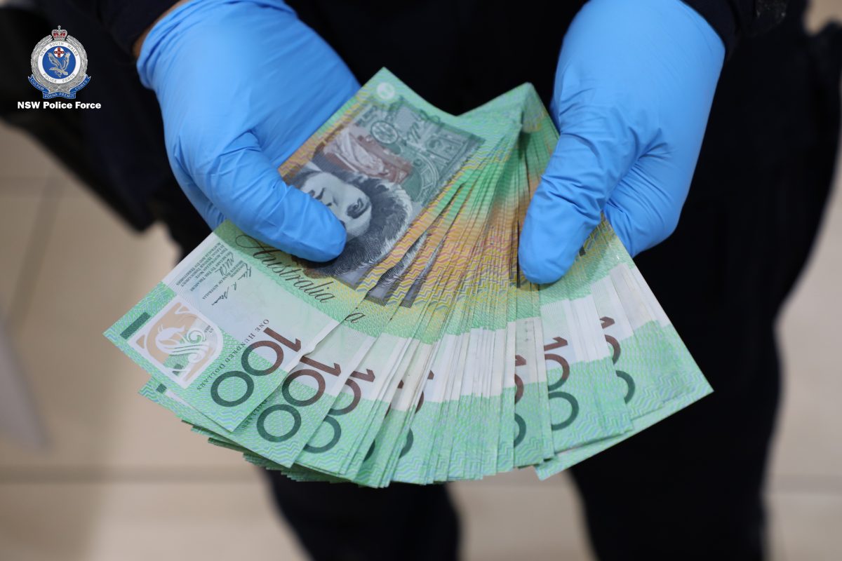 police officer holding stack of one hundred dollar notes