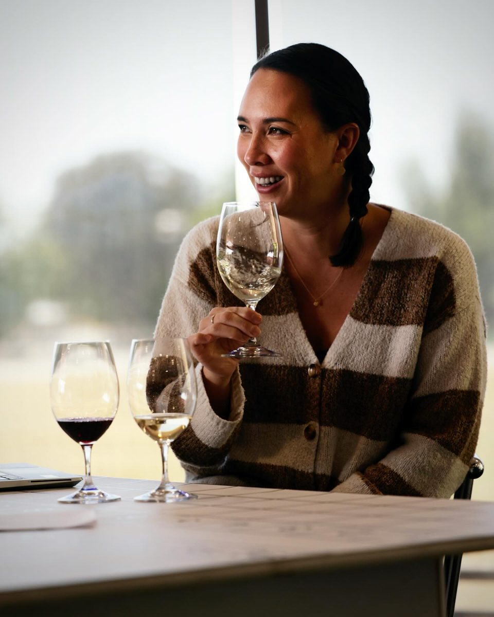 A woman in striped top holds a glass of wine.