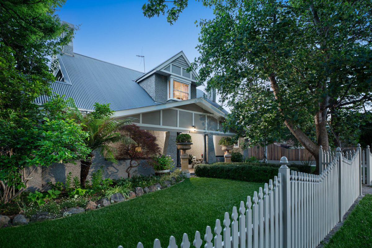 front facade of historic property with lush lawns and white picket fence