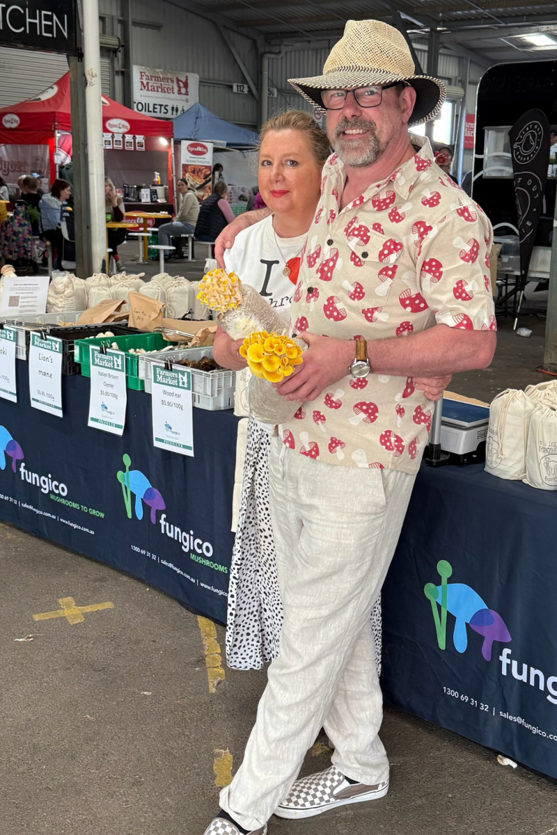 Man and woman smiles at camera in a food market.