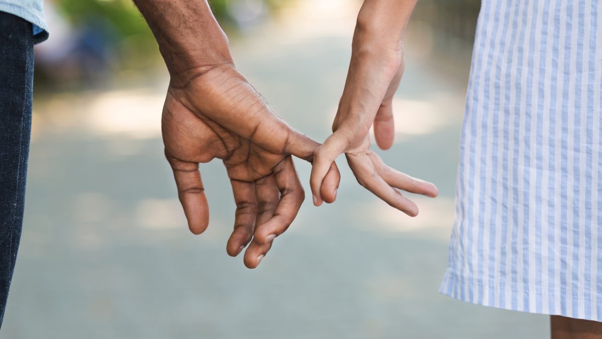 Couple holding little fingers while walking in park