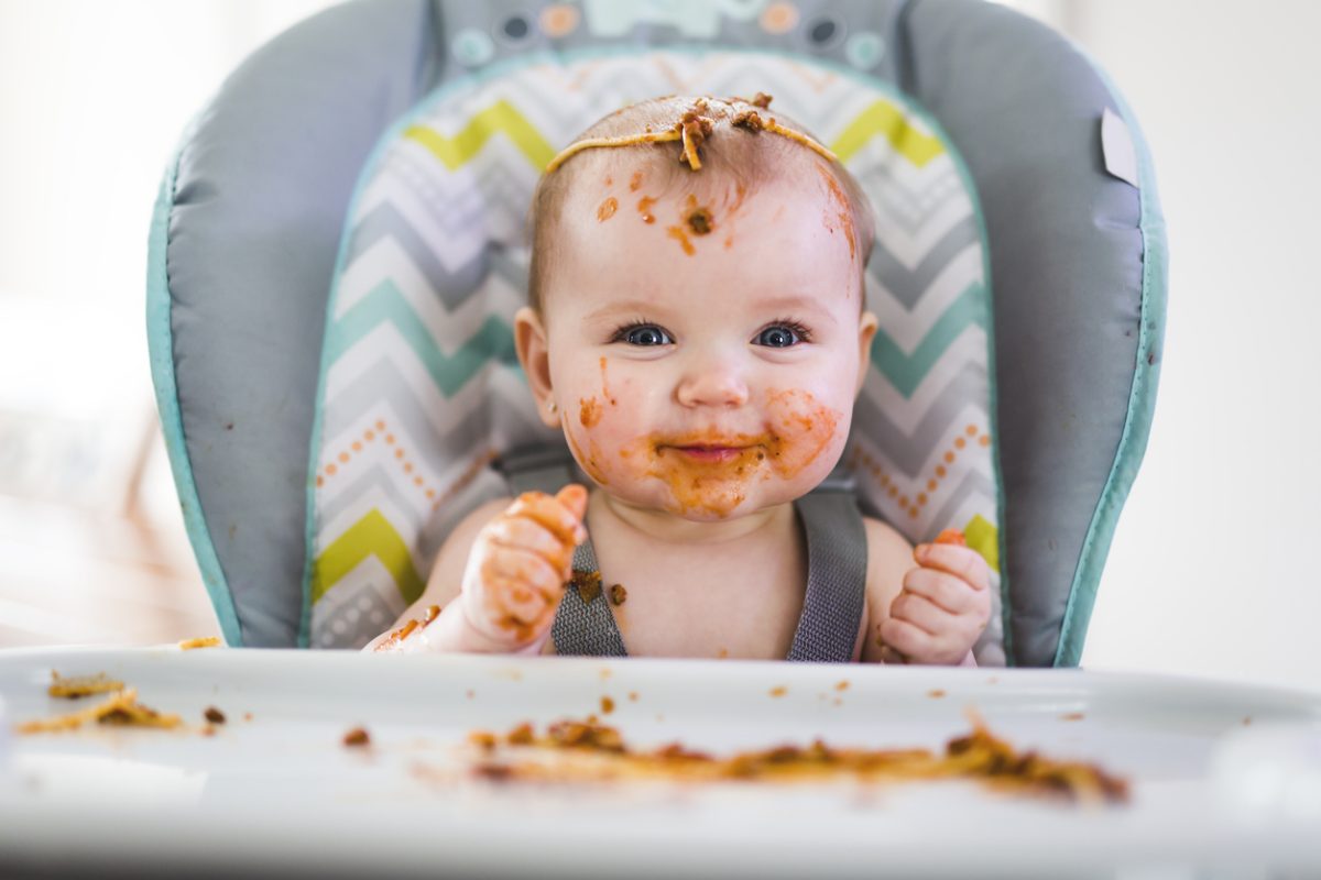 baby with food on her face and hands