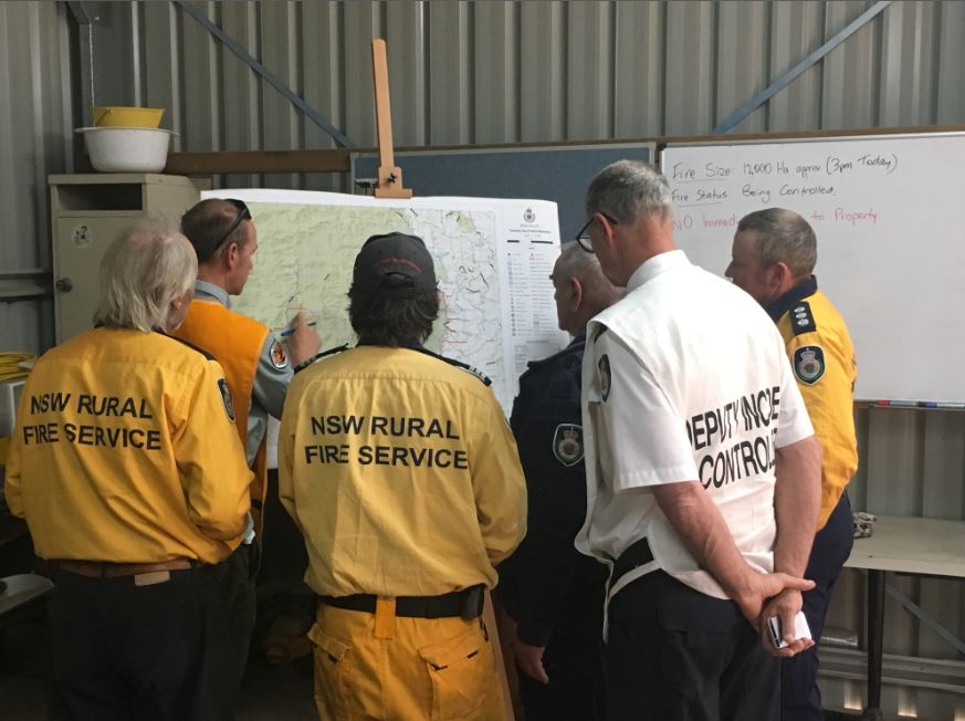 Fire fighters from the RFS and NPWS swap notes ahead of a new week on the Yankees Gap Fire. Photo: Ian Campbell.
