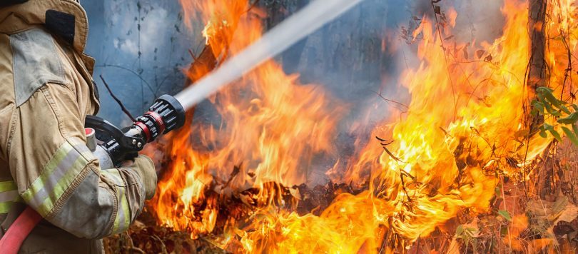 Firefighter with hose battling blaze