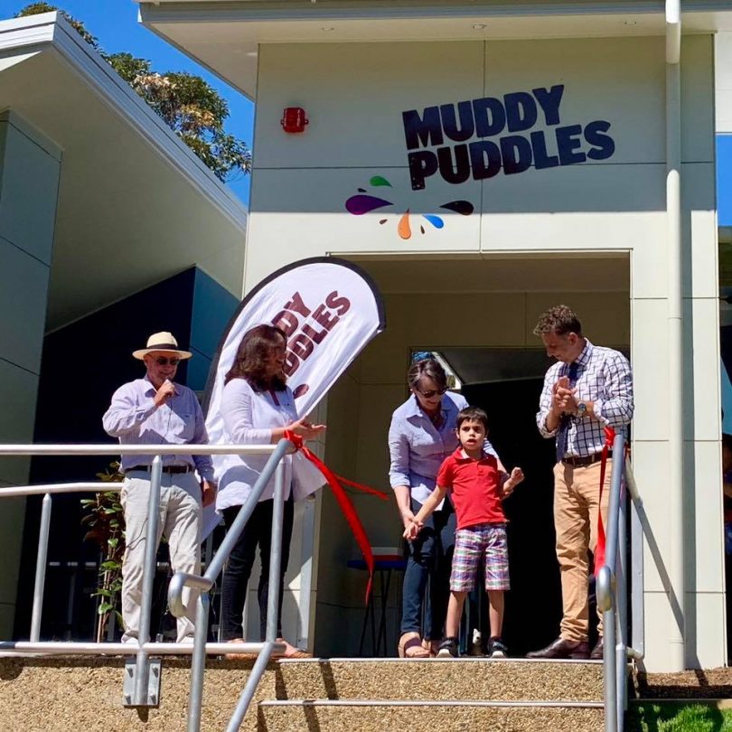 Frankie (in the red shirt) helps Andrew Constance cut the ribbon opening Muddy Puddles. Photo: Muddy Puddles Facebook.