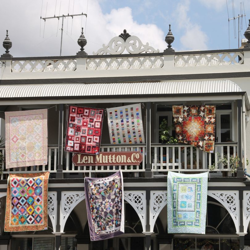 quilts hanging from the balcony of a store