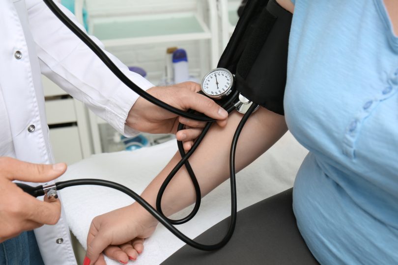 Doctor measuring blood pressure of woman in hospital.