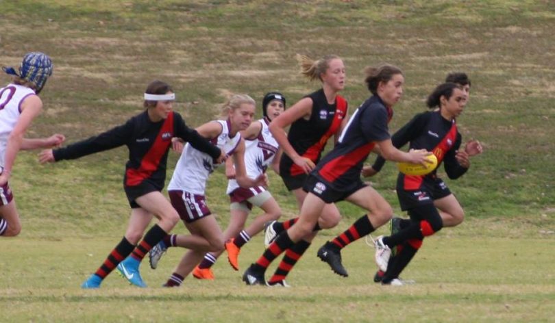 Girls playing Australian rules football for Bega Bombers.
