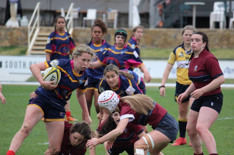 Rugby Union is not for the faint-hearted. Falcon Eleni Ives of Narooma dodges and weaves her way through Canberra's Radford. Falcons won the ACT Girls Rugby 10s competition in 2018 and are currently recruiting 12-18 year old girls for 2019. Photo: Falcons.