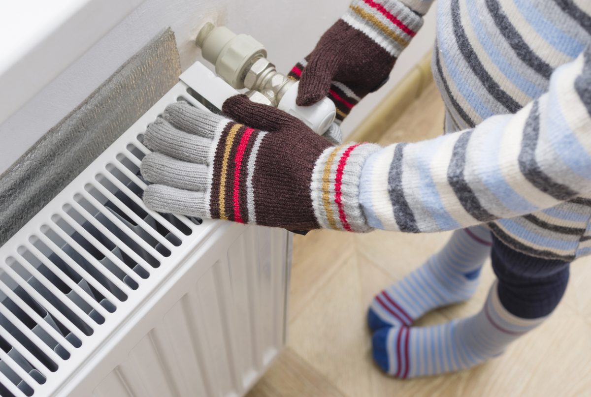 child heating gloved hands over heater