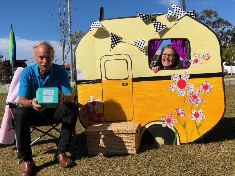 a man with a woman who is behind a cardboard mini-caravan