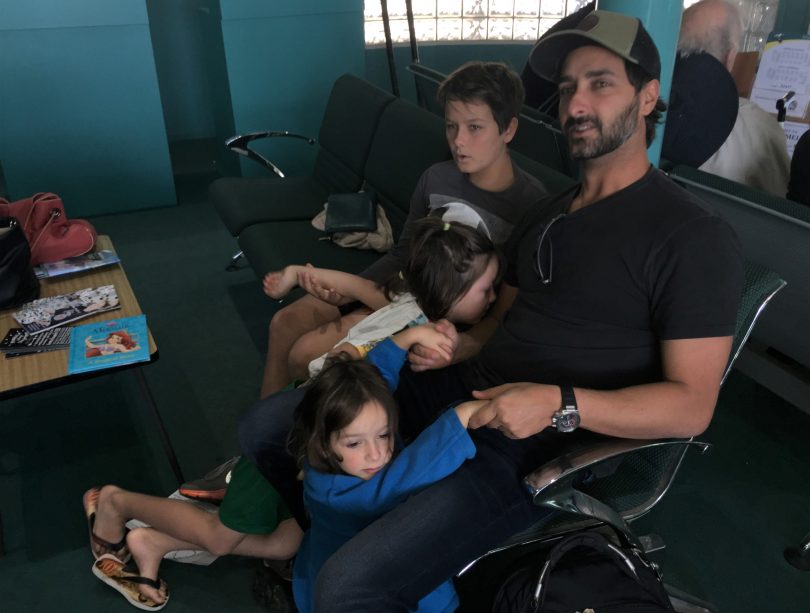 Adelqui Rizotto waits for a flight at Merimbula airport, with his three kid. Photo: Supplied. 
