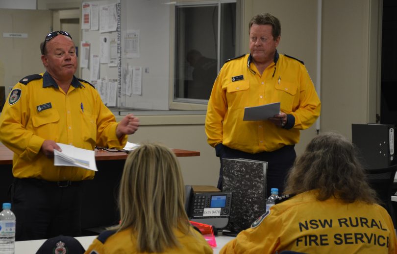 Monaro District Inspector Langdon Gould and Strike team 2041 leader Captain Mark Roarty brief volunteer firefighters yesterday at the Cooma Fire Control Centre.