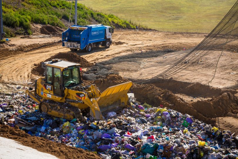 Bulldozer treating waste at landfill.