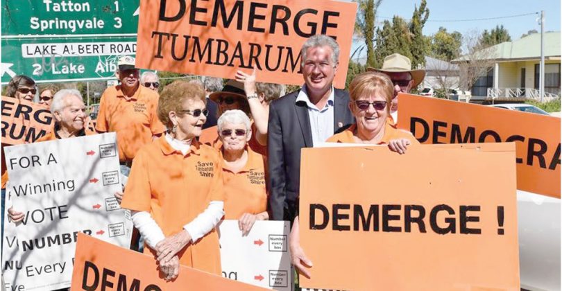 people holding protest placards and posters opposing the merger of Tumbarumba and Tumut shires